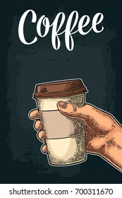 Hand holding a disposable cup with cardboard holder and cap. Coffee lettering. Vintage color vector engraving illustration for label, web. Isolated on dark background