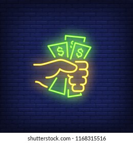 Hand holding dollar bills neon sign. Money, finance and banking concept. Advertisement design. Night bright neon sign, colorful billboard, light banner. Vector illustration in neon style.