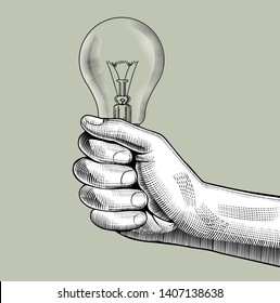 Hand holding a glass light bulb. Vintage engraving stylized drawing. Vector illustration 