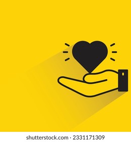 mano sosteniendo el corazón con sombra sobre fondo amarillo