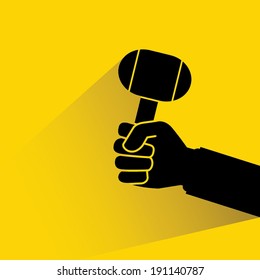 hand holding lump hammer on yellow background, flat and shadow style