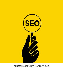 hand holding magnifier seo on yellow background