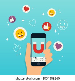 Hand holding mobile smart phone with magnet attracting hearts and reaction smileys. Social media marketing concept. 