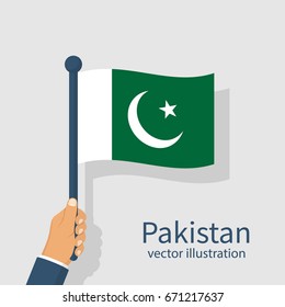 Hand holding a Pakistan flag to celebrate their Independence Day seen as a national holiday. Isolated on bright background.