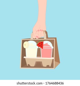 hand is holding the paper bag that has 2 juice smooties with fruit on top (watermelon, banana) inside. take a way beverages. home delivery concept. organic and healthy soft drink for summer.
