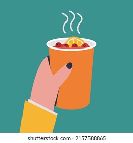 Hand holding a paper cup with hot tea with lemon