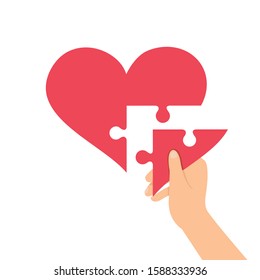 Hand holding a piece of jigsaw, heart is a jigsaw concept, jigsaw is shaped like heart.