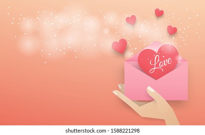 Hand holding a pink envelope with a dark red heart floating out of the envelope with a white spray on the pink background