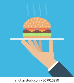  Hand holding a platter with a big hamburger on it
