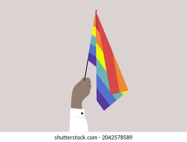 A hand holding a rainbow flag, LGBTQ+ rights, the homosexual community