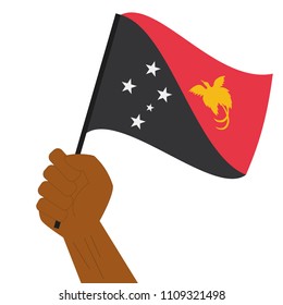 Hand holding and raising the national flag of Papua New Guinea