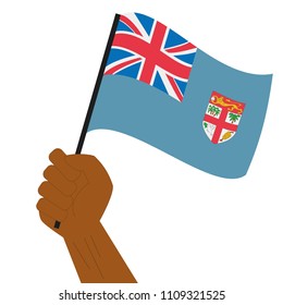 Hand holding and raising the national flag of Fiji