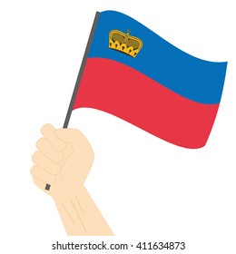 Hand holding and raising the national flag of Liechtenstein