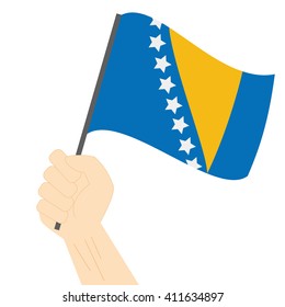 Hand holding and raising the national flag of Bosnia and Herzegovina