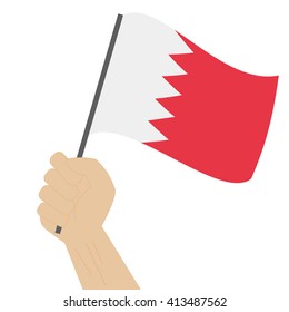 Hand holding and raising the national flag of Bahrain