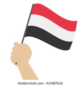 Hand holding and raising the national flag of Yemen