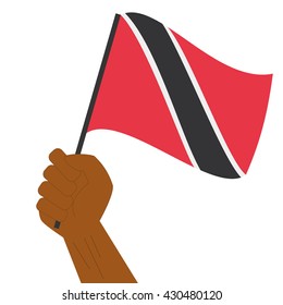 Hand holding and raising the national flag of Trinidad and Tobago