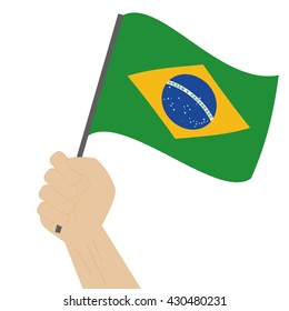 Hand holding and raising the national flag of Brazil