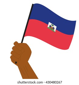 Hand holding and raising the national flag of Haiti
