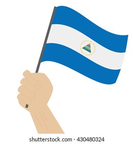 Hand holding and raising the national flag of Nicaragua