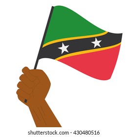 Hand holding and raising the national flag of Saint Kitts and Nevis