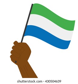 Hand holding and raising the national flag of Sierra Leone