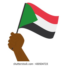 Hand holding and raising the national flag of Sudan