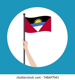 Hand holding and raising the national flag of Antigua and Barbuda. Hand proudly waving the national flag of Antigua and Barbuda.