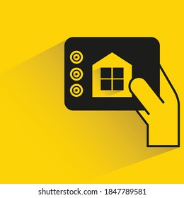 Hand-Halten und Fernsteuerung des intelligenten Zuhause-Konzepts, gelber Hintergrund