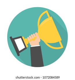 Hand holding and rising up golden trophy icon. Circle shaped with long shadow