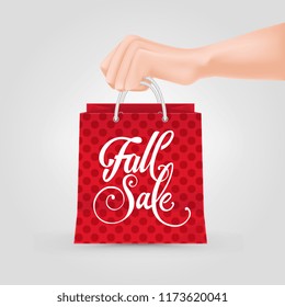 Hand holding shopping bag with fall sale lettering. Fall offer or sale advertising design. Handwritten text, calligraphy. For leaflets, brochures, invitations, posters or banners.