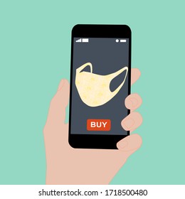 Hand holding smart phone with buy button on the screen. Contactless online purchase of goods using your phone. Use fabric mask. Home delivery. Disease prevention concept.
