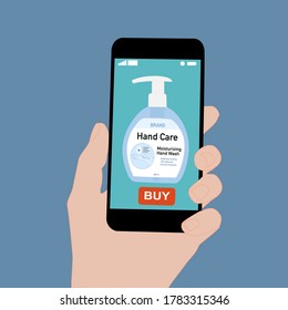 Hand holding smart phone with buy button on the screen. Contactless online purchase of goods using your phone. Use Hand wash soap pump bottle. Diseases prevention. Home deliVery.