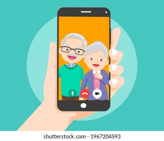 Hand holding smartphone with elderly couple on screen.Video call with grandparents or aging parents.