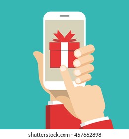 Hand holding smartphone with gift box on the screen. Finger touch the box. Vector flat illustration.