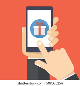 Hand holding smartphone with gift box on the screen. Finger touch the box. Vector flat illustration.