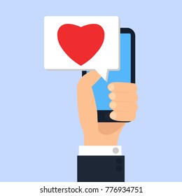 Hand holding smartphone with heart in message on screen, like button. Mobile media device
