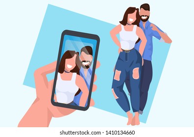 hand holding smartphone and taking photo on camera casual couple embracing man woman standing pose male female cartoon characters posing together flat full length horizontal