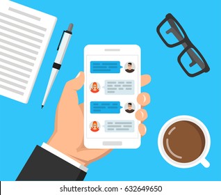 Hand holding smartphone with text messaging on the screen. ?up of coffee, notebook with pen and glasses lay on the table. Vector flat illustration.