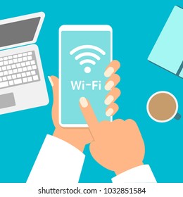 Hand holding smartphone with wifi on the screen. On the desktop, Notepad, coffee Cup. The view from the top. Vector illustration.