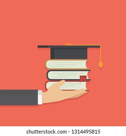 Hand holding stack of book with graduates hat, graduation or scholarship concept