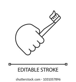 Hand holding toothbrush linear icon. Thin line illustration. Teeth cleaning. Contour symbol. Vector isolated outline drawing. Editable stroke