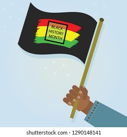 Hand holding waving Black History Month flag with proud as a celebration on blue gradient background
