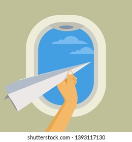 Hand holds a paper plane against the background of airplane window