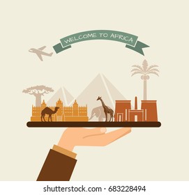 The hand holds the sights of Africa on a tray. The plane and the words welcome to Africa on the ribbon
