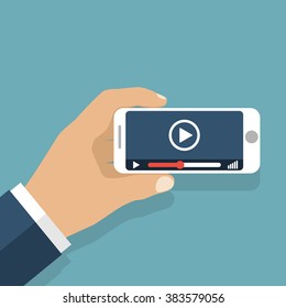 Hand holds smartphone. Video player application on your mobile phone screen. Watching videos on the phone.  Vector flat. Mobile video streaming technologies.
