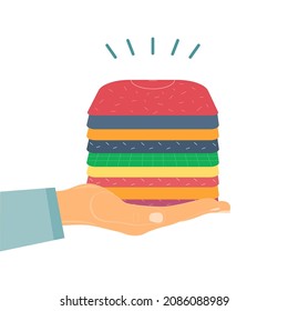 Hand holds a stack of folded donation clothes. Concept of social and humanitarian aid, volunteering and charity.Vector illustration.