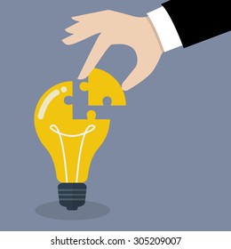 Hand inserts the missing puzzle in lightbulb. Business idea concept