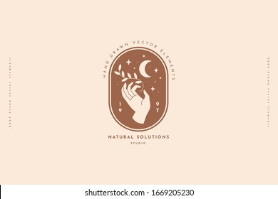 Hand keeps branch with sheets, crescent, stars. Minimal style logo design template. Trendy magic symbol on a light background. Emblem for organic cosmetics and packaging for handmade products.