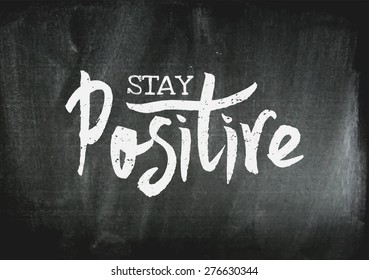 Hand lettered text "Stay Positive" in white on chalkboard background. Inspirational poster, print, clothing design.